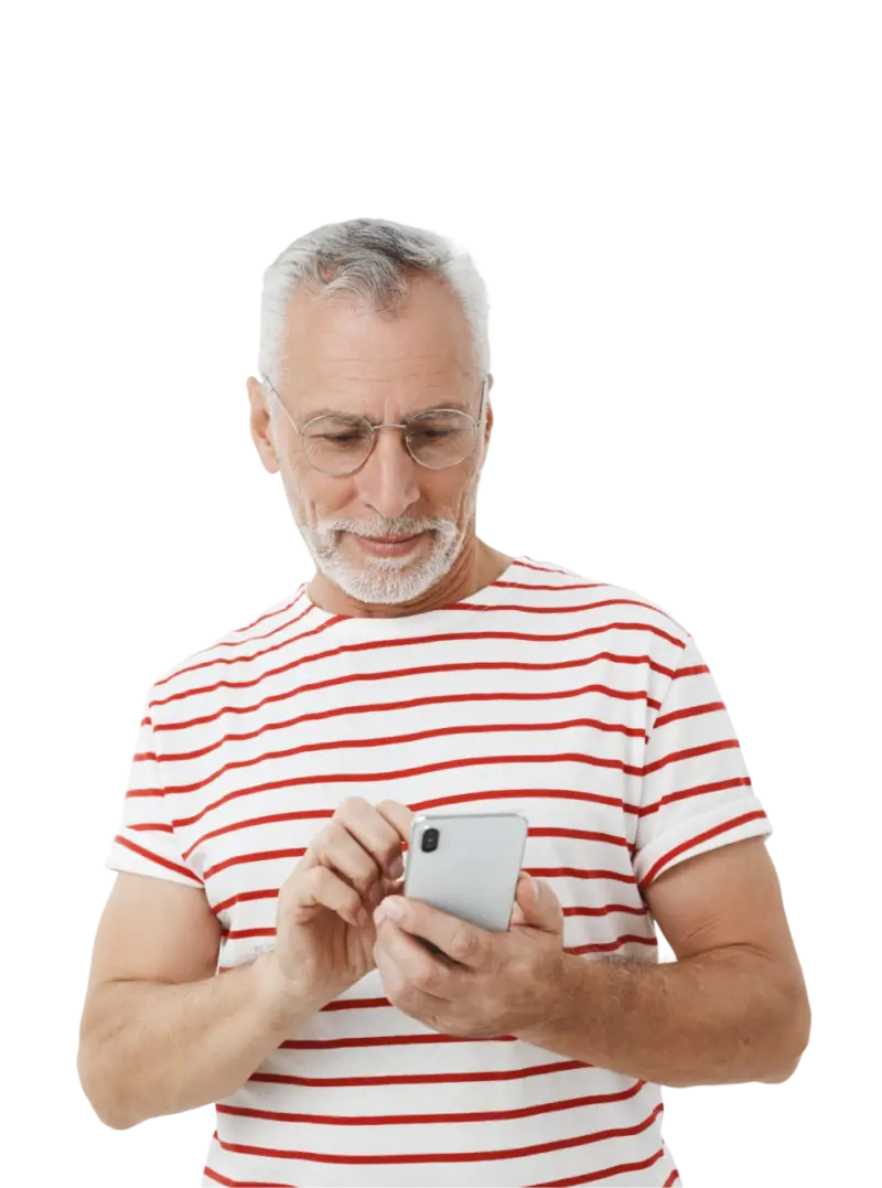 Starszy mężczyzna w siwych włosach i okularach, patrzy na telefon w ręku i przegląda aplikację Galerii Solnej. Ubrany w tshirt w czerwone paski.